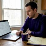 Man reviewing crypto graphs in kitchen workspace
